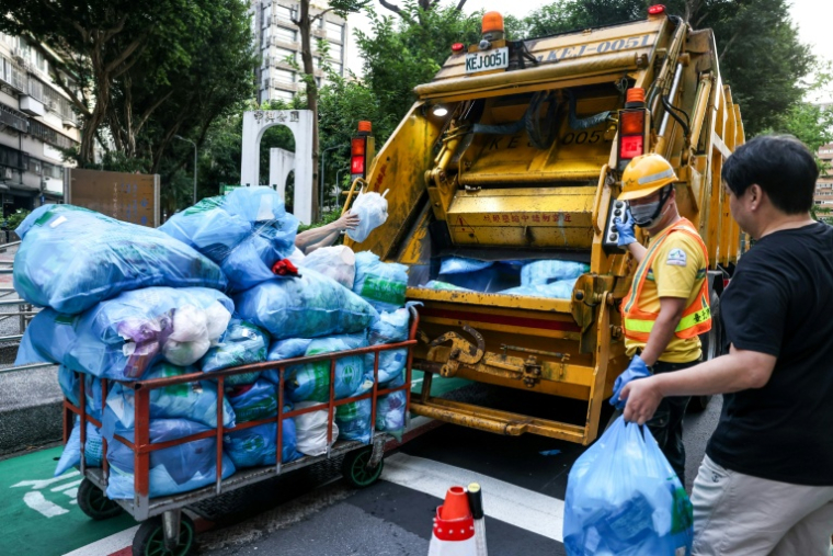 Des habitants de Taipei à Taïwan aidant les éboueurs à jeter leurs ordures dans la benne de leur camion, le 19 juin 2025 ( AFP / I-Hwa Cheng )