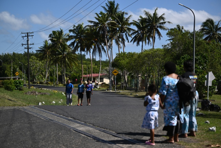 Des habitants marchent sur la route menant au village de Rukurukulevu, aux Fidji, le 9 octobre 2026 ( AFP / Saeed KHAN )