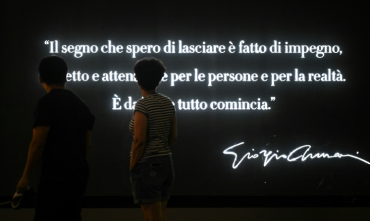 Une femme regarde une citation de Giorgio Armani affichée sur la vitrine de l'hôtel Armani à Milan, le 5 septembre 2025, "La marque que j'espère laisser est faite d'engagement, de respect et d'attention aux personnes et à la réalité. C'est c'est là que tout commence" ( AFP / Stefano RELLANDINI )