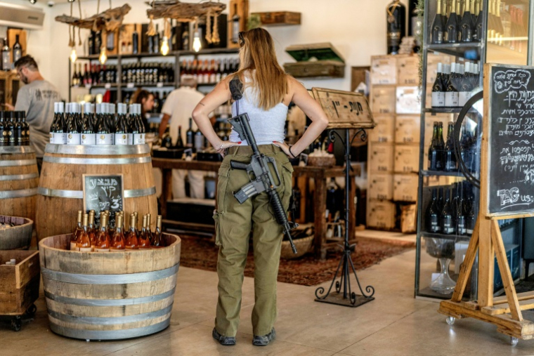 Une soldate de l'armée israélienne regarde des bouteilles de vin en vente dans une exploitation viticole de la colonie israélienne de Shaar Binyamin, au sud-est de Ramallah, le 9 septembre 2026 en Cisjordanie occupée ( AFP / Ilia YEFIMOVICH )