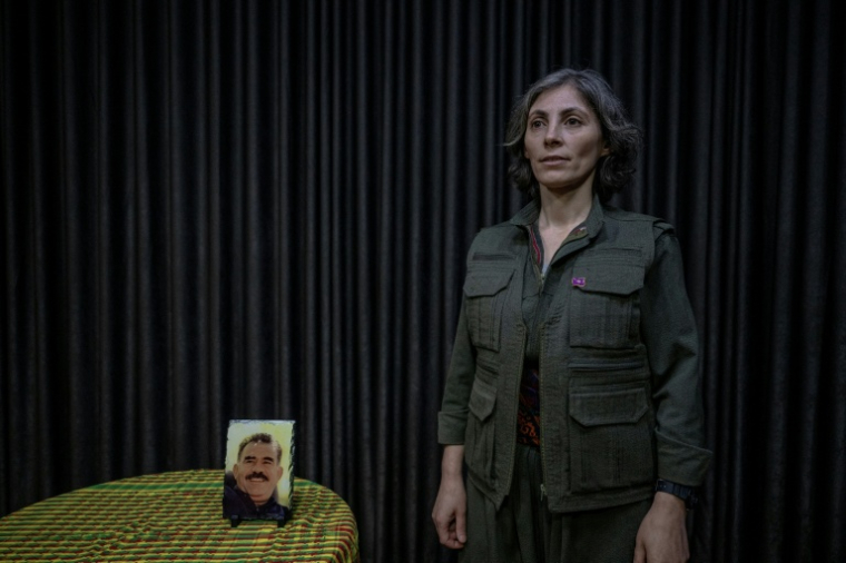 la commandante d'un groupe de rebelles kurdes, Rôken Nerada, à côté d'un portrait d'Abdullah Öcalan, le chef emprisonné du Parti des travailleurs du Kurdistan (PKK), lors d'une interview près de la frontière irako-iranienne, dans la région autonome du Kurdistan irakien, le 8 mars 2026 ( AFP / - )