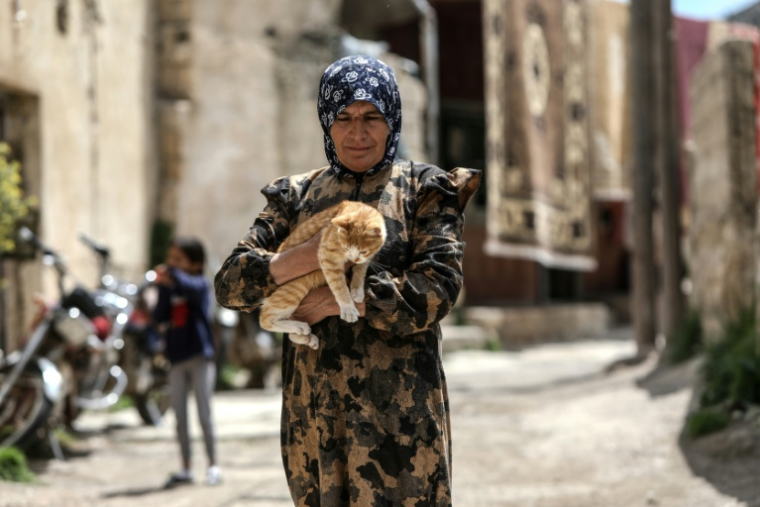 Fatima al-Safadi porte son chat dans les rues de son village de Beit Jinn, le 29 avril 2026 dans le sud de la Syrie  ( AFP / Bakr ALKASEM )