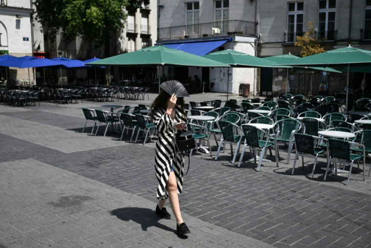 Une passante se protège du soleil avec un éventail, le 23 juin 2026 à Nantes ( AFP / Sebastien Salom-Gomis )