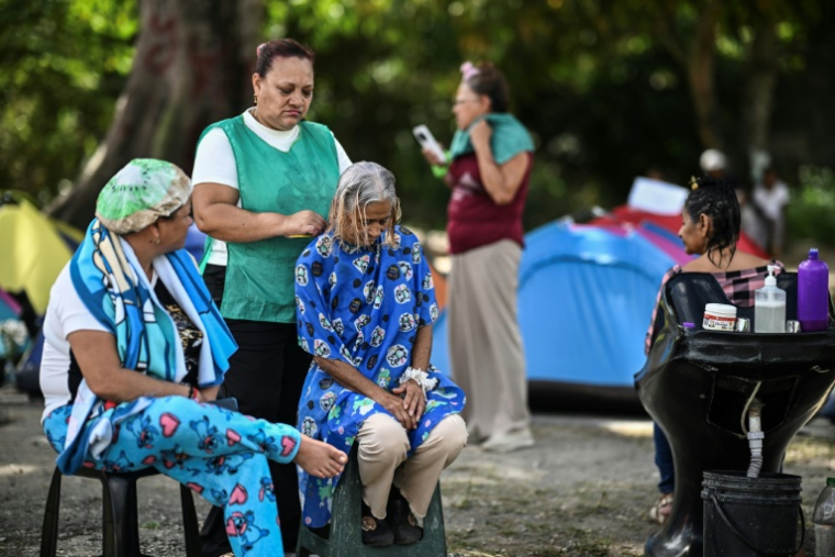 Melba Vazquez (au centre), mère du prisonnier politique Merwin Simons, reçoit un soin capillaire devant la prison Rodeo I où elle attend la sortie de son fils, le 25 janvier 2026 à Guatire, près de Caracas, au Venezuela ( AFP / Ronaldo SCHEMIDT )