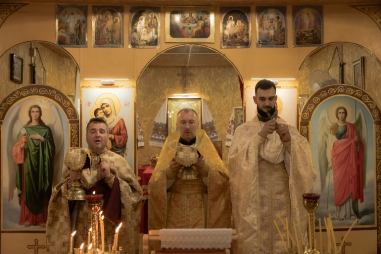 Des prêtres ukrainiens dirigent un service de prière à l'église des saints martyrs Vira, Nadia, Lyubov et Mère Sophie de l'Église orthodoxe d'Ukraine, alignée sur Kiev, le 13 juillet 2025 à Kramatorsk  ( AFP / Roman PILIPEY )