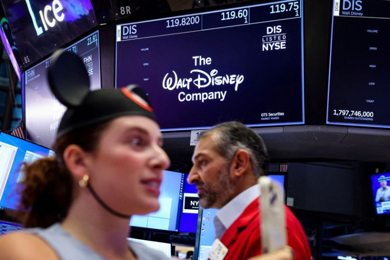 Un écran affiche le logo et les informations boursières de The Walt Disney Company tandis que des traders travaillent sur le parquet de la Bourse de New York (NYSE) à New York