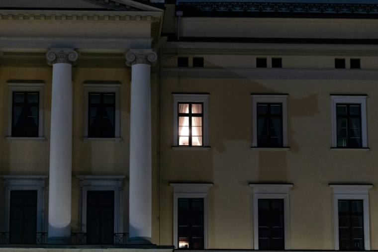 Une lumière est visible à une fenêtre du Palais royal alors que des personnes se rassemblent pour une veillée nocturne en l'honneur du roi Harald V de Norvège, sur la place du Palais à Oslo, tôt le 28 août 2026. ( AFP / Odd ANDERSEN )