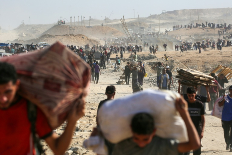 Des Palestiniens marchent avec des sacs d'aide humanitaire distribuée par la Gaza Humanitarian Foundation (GHF), à Nuseirat dans la bande de Gaza le 26 septembre 2025 ( AFP / Eyad BABA )