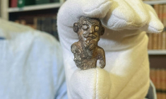 Le conservateur du musée national du Danemark, Peter Pentz, montre une figurine en ivoire de morse, pièce d'un jeu de société, qui serait le premier portrait d'un Viking, le 26 août 2025 à Copenhague ( AFP / Camille BAS-WOHLERT )