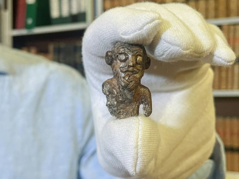 Le conservateur du musée national du Danemark, Peter Pentz, montre une figurine en ivoire de morse, pièce d'un jeu de société, qui serait le premier portrait d'un Viking, le 26 août 2025 à Copenhague ( AFP / Camille BAS-WOHLERT )