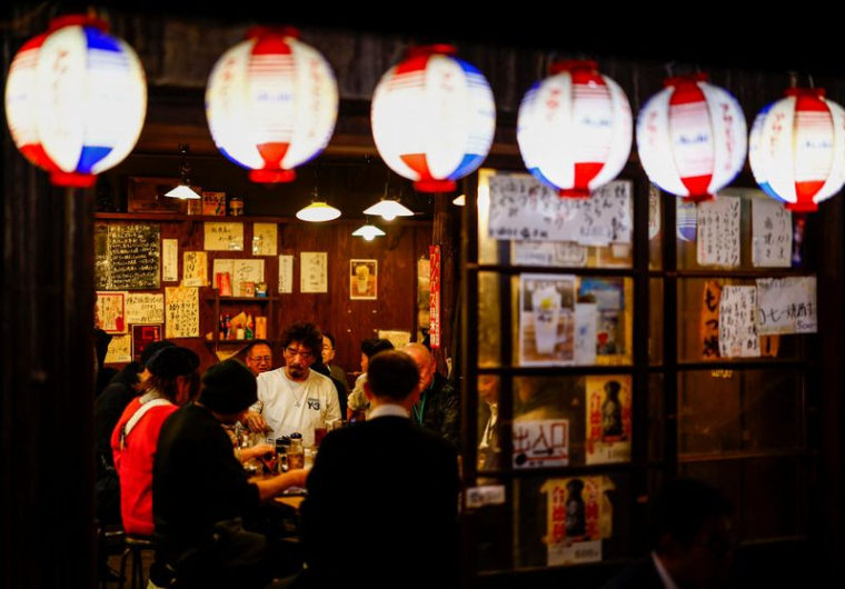 Des personnes boivent et mangent dans un pub izakaya dans le quartier commerçant d'Ameyoko, à Tokyo
