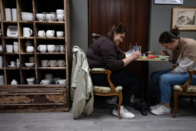 Des participants peignent des assiettes lors d'un atelier dans un "café céramique" à Strasbourg, le 21 avril 2026 dans le Bas-Rhin ( AFP / SEBASTIEN BOZON )