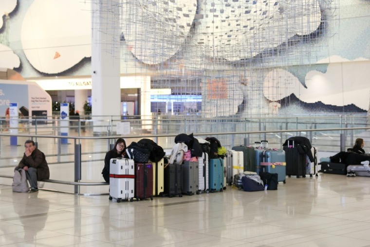 Des passagers en attente le 23 mars 2026  à l'aéroport LaGuardia de New York, fermé après une collision entre un avion et un véhicule de l'autorité portuaire dans la nuit ( AFP / TIMOTHY A.CLARY )