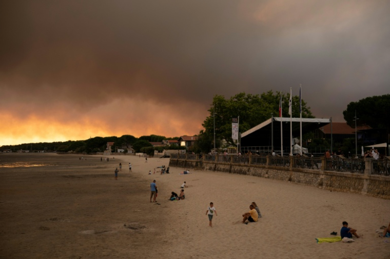 Des touristes sur la plage d'Andernos-Les Bains près de Lège Cap-Ferret où sévit un important incendie, le 23 juillet 2026  ( AFP / Olivier MORIN )