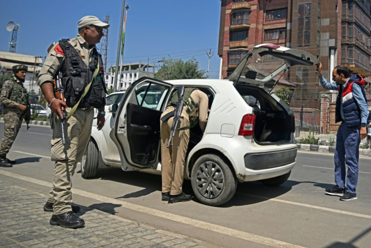 Des paramilitaires indiens montent la garde pendant qu'un policier inspecte un véhicule dans une rue de Srinagar, le 30 avril 2025 au Cachemire indien ( AFP / Tauseef MUSTAFA )