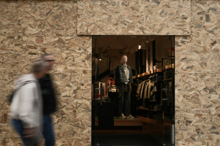 Des passants devant un magasin de vêtements dont les vitrines ont été protégées en prévision d'une nouvelle manifestation, le 24 octobre 2026 à Bordeaux  ( AFP / Philippe LOPEZ )