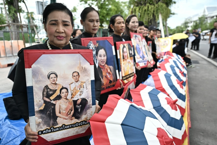 Des personnes en deuil tiennent des portraits de la défunte princesse thaïlandaise Bajrakitiyabha Mahidol devant le Grand Palais de Bangkok, le 13 juin 2026 ( AFP / Lillian SUWANRUMPHA )