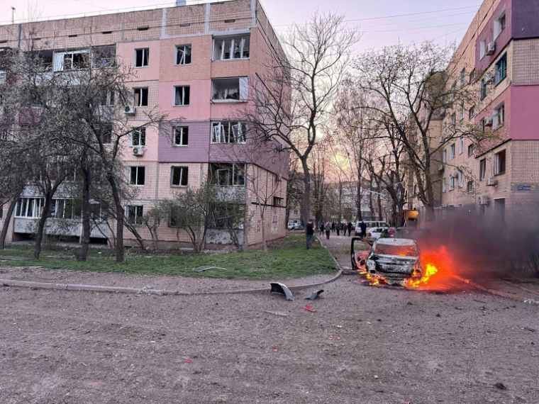 Photo diffusée sur le canal Telegram officiel du président ukrainien Volodymyr Zelensky, le 4 avril 2025, montrant une voiture en feu près d'immeubles endommagés par une frappe de missile russe à Kryvyi Rig, dans la région de Dnipropetrovsk ( Telegram / @V_Zelensky_official / - )