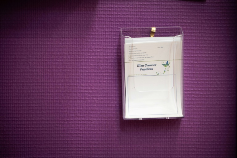 Du papier à lettres placé sur un mur à côté d'une boîte aux lettres pour les élèves mise en place par l'association "Les Papillons" en cas d'abus à l'école, le 12 mai 2025 à l'école élémentaire Blanche à Paris ( AFP / LEO VIGNAL )