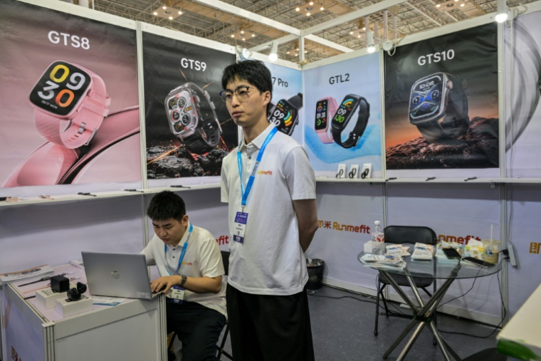 Han Zhongkai, employé d'une entreprise technologique fabriquant notamment des montres intelligentes, sur son stand à la foire commerciale de Ningbo, dans la province orientale du Zhejiang, le 29 mai 2025 en Chine ( AFP / Hector RETAMAL )