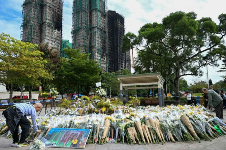 Des personnes déposent des fleurs et rendent hommage aux victimes de l'incendie meurtrier de Wang Fuk Court, le 1er décembre 2025 à Hong Kong ( AFP / Peter PARKS )