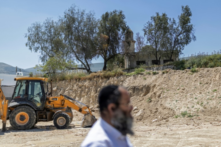 Un colon israélien passe devant un bulldozer dans la colonie de Sa-Nur, en Cisjordanie occupée, le 7 mai 2026. ( AFP / ilia YEFIMOVICH )