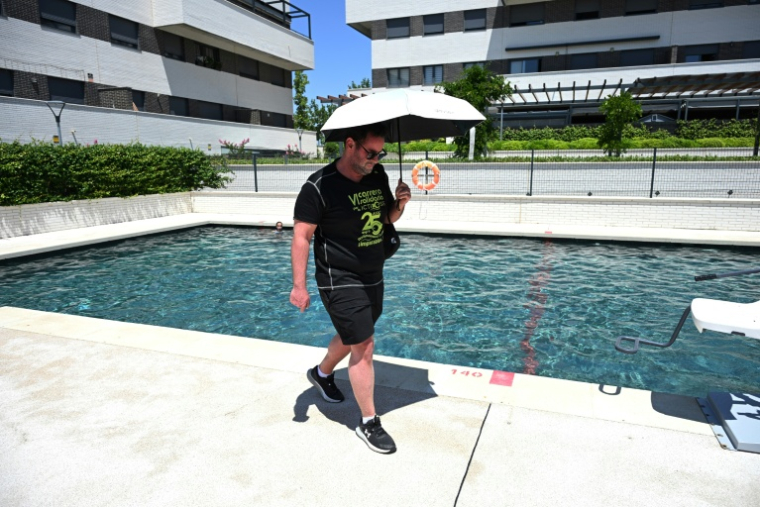 L'Espagnol Alberto Gomez, professeur de physique-chimie, atteint d'ichtyose, se protège du soleil avec un parapluie à Arroyomolinos, près de Madrid, le 1er juillet 2026 ( AFP / Javier Soriano )
