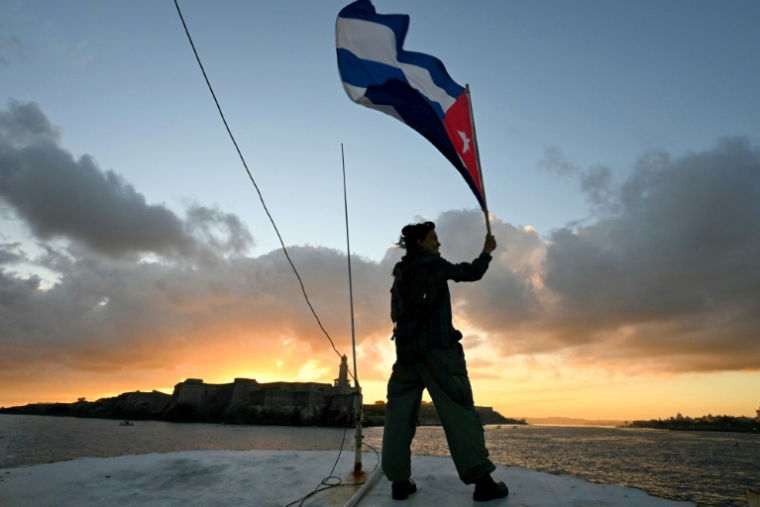 Un militant tient un drapeau cubain sur le pont du bateau de pêche Maguro, faisant partie de la flottille d'aide humanitaire, à son arrivée dans le port de La Havane, le 24 mars 2026 ( AFP / Yuri Cortez )