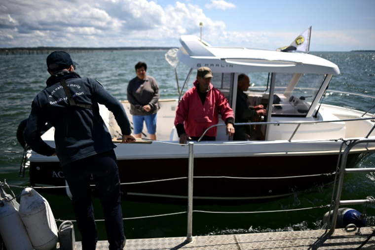 Des agents de la police de l'environnement de l'OFB transmettent des consignes de prévention aux plaisanciers pour les empêcher de mouiller dans les zones réglementées où l'habitat aquatique des zostères est surveillé et développé pour lutter contre l'érosion et l'ensablement, du Bassin d'Arcachon, le 13 mai 2025 en Gironde ( AFP / Christophe ARCHAMBAULT )