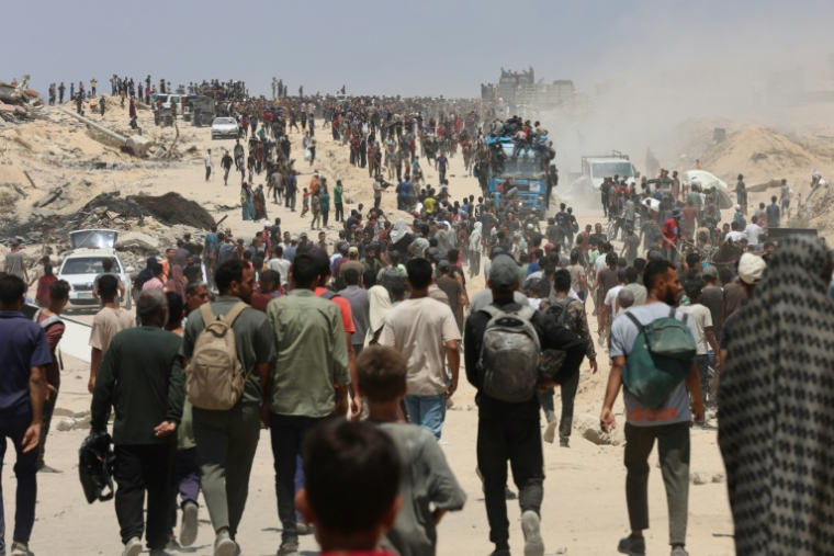 Des Palestiniens à Jabalia dans le nord de la bande de Gaza se dirigent vers des camions transportant de l'aide humanitaire, le 22 juillet 2025 ( AFP / Omar AL-QATTAA )