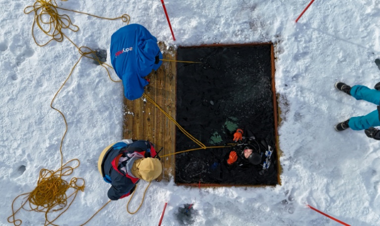 Un plongeur participe à un stage scientifique de plongée polaire, le 14 mars 2026 dans le lac de Kilpisjärvi, à l'extrême nord-ouest de la Finlande ( AFP / Jonathan KLEIN )