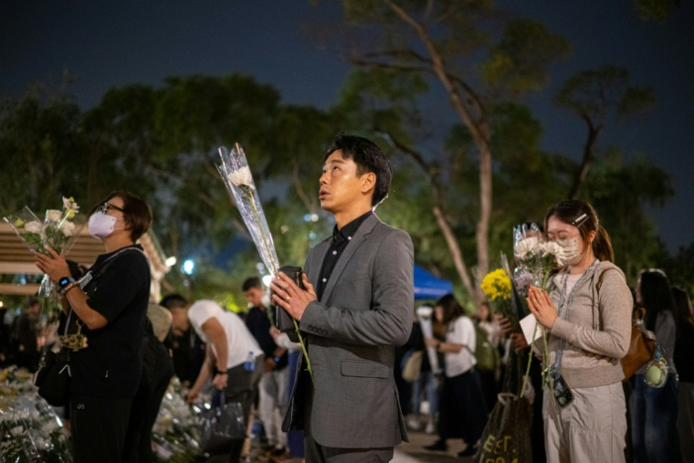 Des personnes se recueillent le 2 décembre 2025 à Hong Kong devant un complexe résidentiel dont l'incendie a fait au moins 159 morts le 26 novembre ( AFP / Philip FONG )