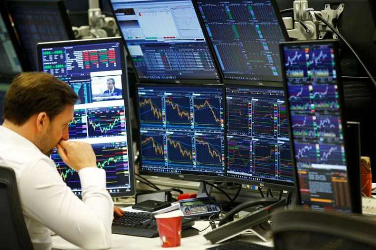 Chez CMC Markets à Londres, les traders travaillent à leur bureau tandis que des écrans affichent les données de marché
