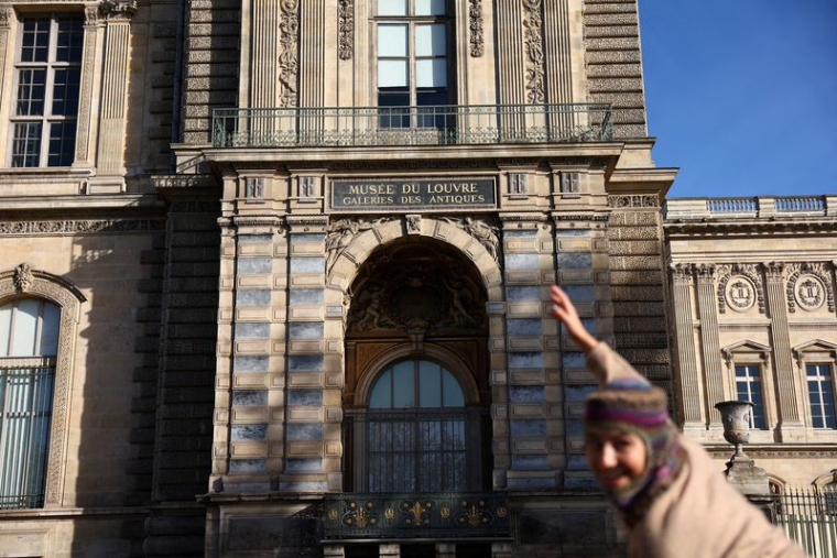 Une personne pose devant une fenêtre à l'étage qui a été brisée par des voleurs pour entrer dans le musée du Louvre