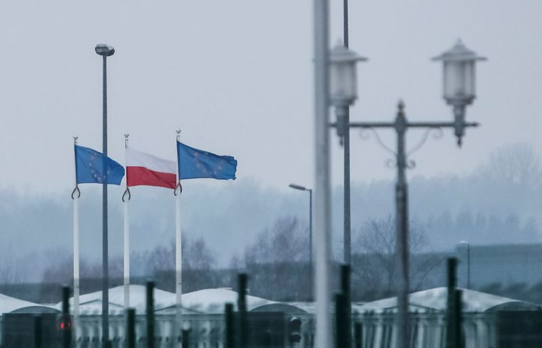 Une vue sur la frontière biélorusse-polonaise montre des drapeaux polonais et européens derrière une clôture