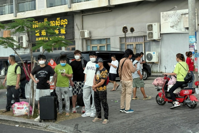 Des personnes dans une rue après avoir quitté un complexe suspecté d'être un centre d'escroquerie près du casino Amber à Sihanoukville, le 15 janvier 2026 au Cambodge ( AFP / TANG CHHIN Sothy )
