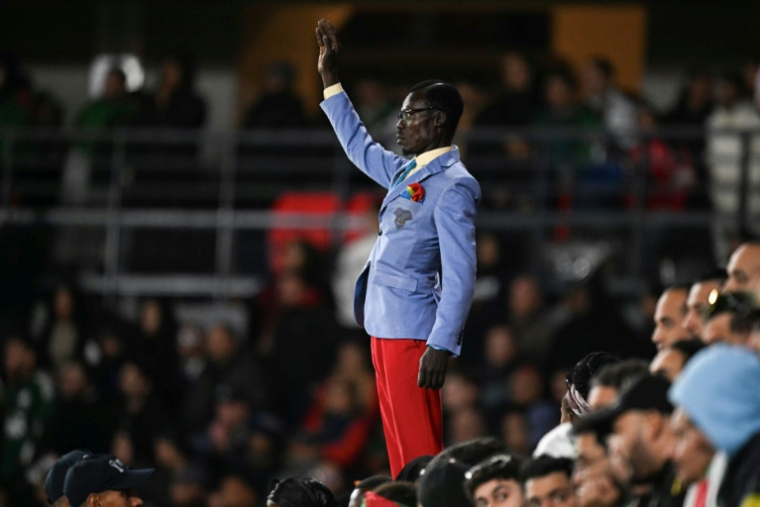 Le supporter congolais Michel Kuka Mboladinga rend hommage à l'ancien Premier ministre congolais, Patrice Lumumba, debout, le bras levé, avant le match de huitièmes de finale de la CAN entre l'Algérie et la RDC au stade Prince Moulay El Hassan de Rabat, le 6 janvier 2026 au Maroc ( AFP / Gabriel BOUYS )