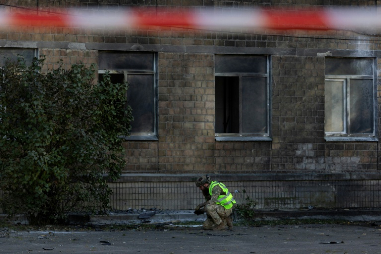 Un policier ukrainien inspecte des débris près d'un bâtiment endommagé par une frappe de drone russe à Kiev, le 1er octobre 2026 ( AFP / Tetiana DZHAFAROVA )
