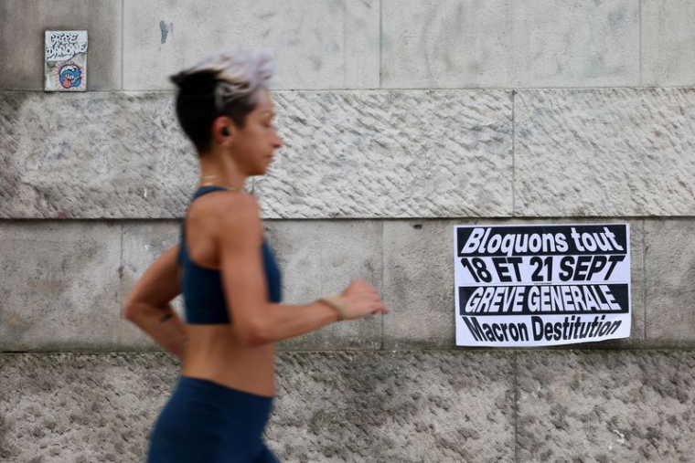 Une femme passe devant une affiche sur laquelle on peut lire "Bloquez tout. Grève générale" à Paris