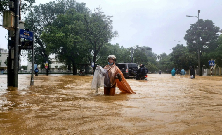 Une femme tente de traverser le 28 octobre 2025 une rue inondée de l'ancienne ville impériale de Hué, dans le centre du Vietnam, qui a enregistré des précipitations de plus d'un mètre en 24 heures, un record ( AFP / STR )