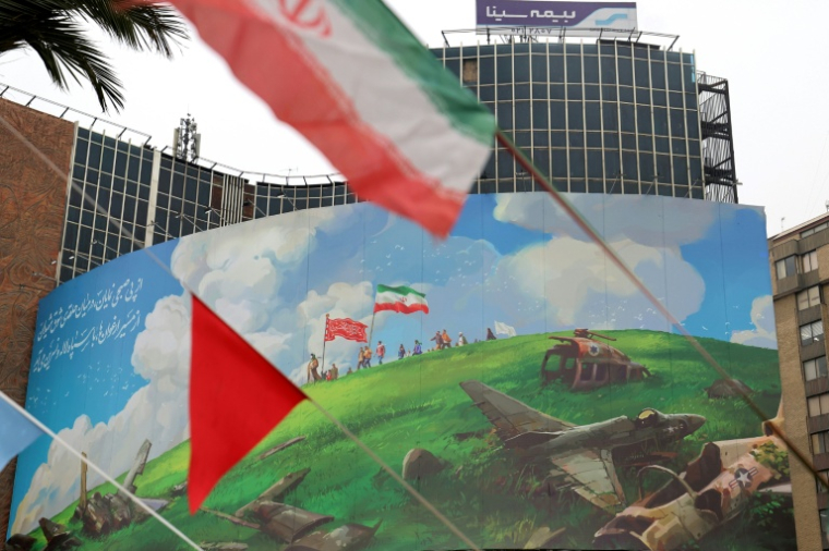 Dans le centre de Téhéran, le drapeau iranien flotte devant un vaste panneau anti-américain, le 8 février 2026 ( AFP / ATTA KENARE )