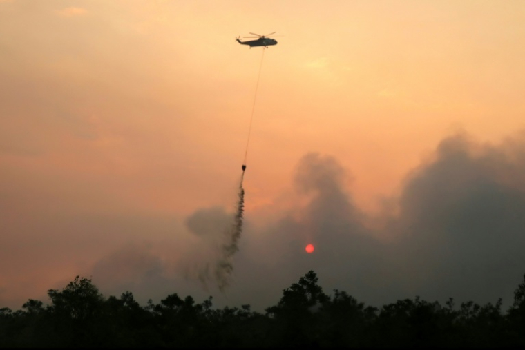 Un hélicoptère largue de l'eau sur des forêts et des terres en feu dans la région de Petuk Katimpun, à Palangkaraya, dans la province du Kalimantan central, en Indonésie, le 13 août 2026A helicopter drops water on burning forests and land in the Petuk Katimpun area, Palangkaraya, in Indonesia's Central Kalimantan province, on August 13, 2026. ( AFP / REINA )