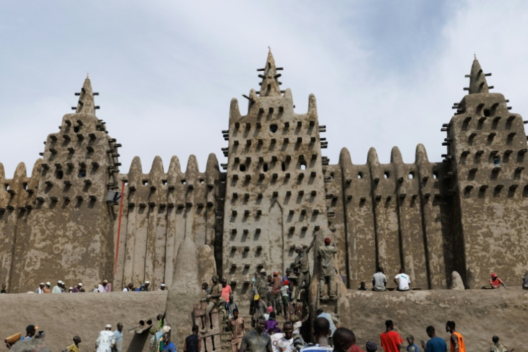 Des personnes utilisent du banco, un enduit de terre, pour le crépissage annuel de la grande mosquée de Djenné le 12 juin 2025 ( AFP / OUSMANE MAKAVELI )