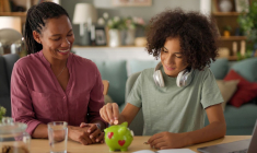 (Crédits photo : Adobe Stock - Mère de famille initiant son adolescent aux sujets bancaires et financiers)