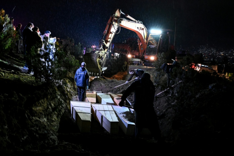 Des personnes déposent dans une fosse commune les cercueils de victimes tuées lors d'une frappe aérienne pakistanaise contre un hôpital pour toxicomanes, le 18  mars 2018 à Kaboul ( AFP / Wakil Kohsar )