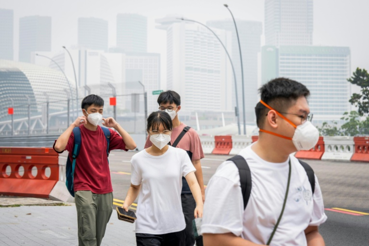 Des passants équipés de masques dans une rue de Singapour le 16 octobre 2026 ( AFP / Yuichi YAMAZAKI )