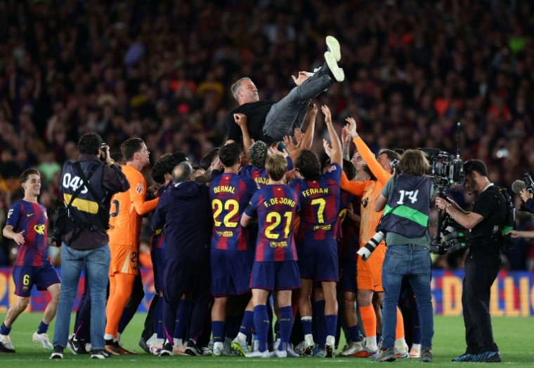 L'entraineur du Barça Hansi Flick porté en triomphe par ses joueurs après la victoire dans le Clasico face au Real Madrid, synonyme de titre de champion d'Espagne, le 10 mai 2026 au Camp Nou ( AFP / Josep LAGO )