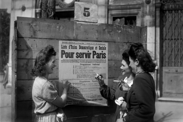 Des femmes devant une affiche électorale pour les élections municipales, avant de voter pour la première fois en France, le 29 avril 1945 à Paris ( AFP / - )
