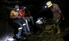 Des mineurs illégaux font une pause tandis qu'un autre pousse une brouette remplie de charbon dans la mine de Golfview à Ermelo le 25 septembre 2025, en Afrique du Sud ( AFP / EMMANUEL CROSET )