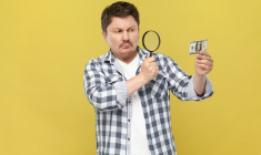 (Commerçant inspectant un billet lors d'un paiement en espèces - Crédit photo : Adobe Stock)